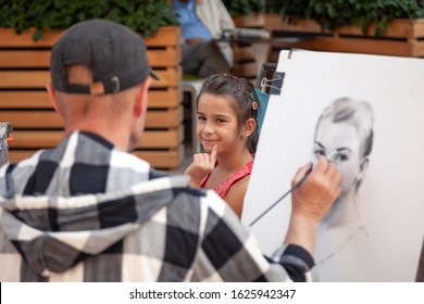 Russia Moscow 2019-06-17 Street Artist Draws Sketch Portrait Of A Beautiful Girl. Street Painter Draws Portrait Of Girl Outdoors.