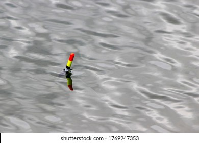 Russia, Moscow, 22.06.2020. Fishing Float (bobber) Against The Background Of Water Close-up. Small Waves And Reflections Of The Sun On The Surface Of The Water. Fishing Concept And Place For Text.