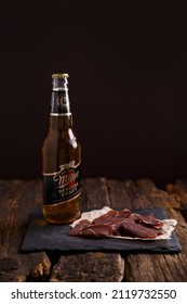 Russia, Moscow,  February 8, 2022. Miller Light Beer With An Appetizer On A Wooden Table, Dark Picture. 