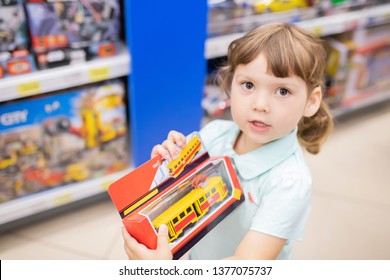 RUSSIA, Moscow. July 03, 2018. Little Kid At The Children Shop, Choosing Toys, Lifestyle. Boy's Toy For Little Girl