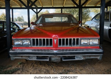 Russia, Moscow - September 2022. Old Retro Vintage Pontiac Red Sports Car Of The 20th Century With Chrome Bumpers Stands Outside Under Canopy At Car Show. Front View.