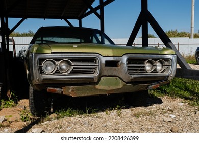 Russia, Moscow - September 2022. Old Retro Vintage Green Rusty American Sports Car Of 20th Century Stands Outside Under Canopy At Car Show. Front View. Chrome Shiny Bumper.