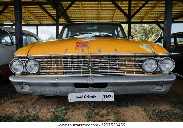 Russia, Moscow - September 2022. An old retro\
vintage sports car Ford Galaxie yellow of the 20th century with\
chrome bumpers stands outside under canopy at exhibition of cars.\
Front view.