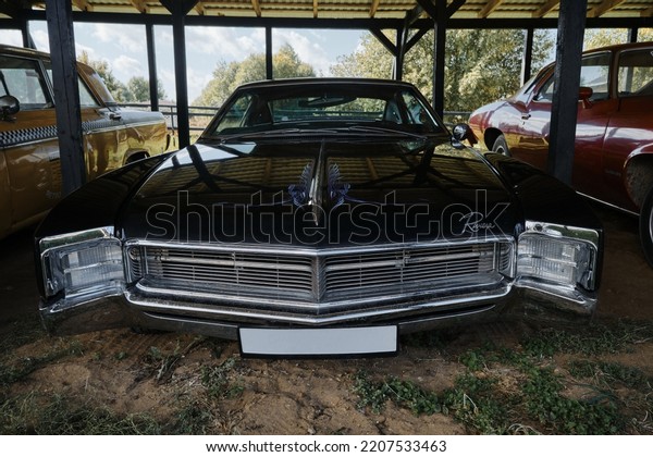 Russia, Moscow - September 2022. Old retro vintage\
Buick Riviera sports car of dark blue color of 20th century with\
chrome bumpers stands outside under canopy at exhibition of cars.\
Front view.