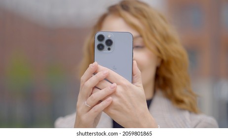 RUSSIA, MOSCOW - SEPTEMBER 27, 2021: Woman takes photos on new iPhone. Action. Woman tests camera of new iPhone 13. New iPhone with three cameras and professional shooting quality