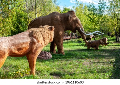 Russia, Moscow - September 29, 2018: Ice Age hunting. A prehistoric lion attacks a herd of mammoths with babies. Life-size models in nature