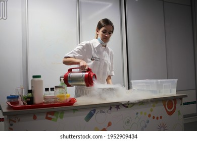 Russia, Novosibirsk 20.09.2020: A Young Scientist In A White Coat And Mask Shows A Scientific Experiment With Liquid Nitrogen In The Galileo Laboratory