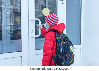 RUSSIA, ROSTOV-ON-DON - October 20, 2020: Schoolboy In Medical Face Mask Pulls Door Handle Before Entering School. New Reality, Restrictions To Prevent Covid Pandemic. Healthcare Concept