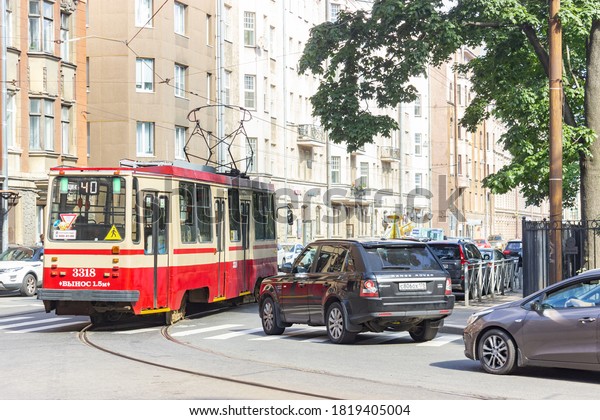 Russia, Saint Petersburg, 09.08.2020. An old\
red tram goes near the park through a pedestrian crosswalk. traffic\
jam on the road. editorial use\
only.