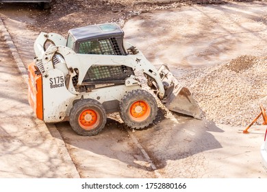 Russia Samara April 2020: Utility Tractor Mini Loader Bobcat S175 Rakes Gravel During Repair Of Asphalt On A City Street.