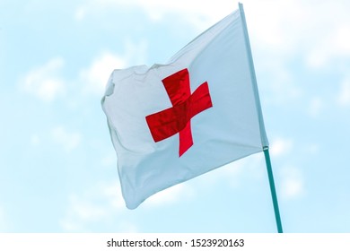 Russia, Samara, June 2019: flag with a red cross develops against a blue sky. Red Cross emblem of the international Red Cross, international humanitarian organizations.