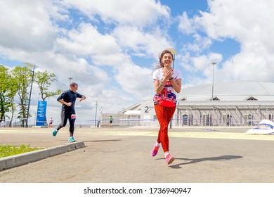 Russia, Samara, May 2019: beautiful athletic girl runs at a city sports event, race, against the background of a new stadium - Shutterstock ID 1736940947