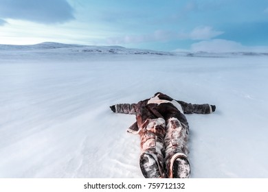 Russia, Siberia, Yamal. Lying In The Snow Man In Nenets Warm Clothes. At A Cold Temperature.