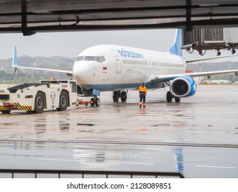 Russia, Sochi 02.11.2021. An Airplane With The Inscription Pobeda Stands On The Runway With An Airport Tug On A Rainy Day.