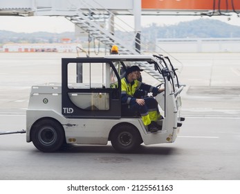 Russia, Sochi 02.11.2021. An Airport Mulag Car With Two Airport Employees In Overalls Is Driving Along The Airfield