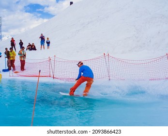 Russia, Sochi 11.05.2019. A guy on a snowboard crosses a pool of water without falling. Snowboard competition on the water in the Krasnaya Polyana ski resort.
