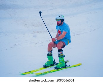 Russia, Sochi 11.05.2019. A Guy On Green Skis Holds A Selfie Stick With A Go Pro Camera And Takes Pictures Of His Ride. Krasnaya Polyana