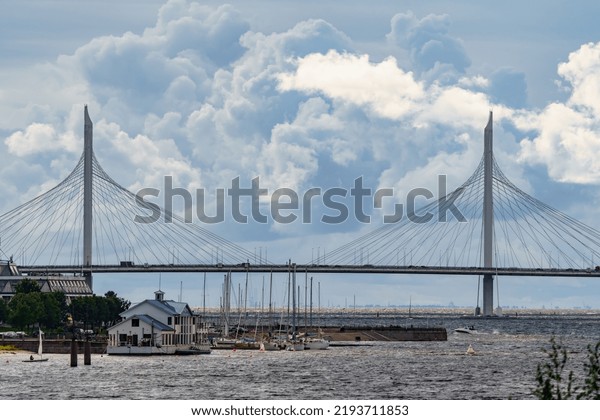 Russia, St.\
Petersburg, 29 July 2022: The embankment of the central yacht club\
at cloudy weather, piers in marina, small sports sailing boats,\
Cable-stayed bridge on\
background