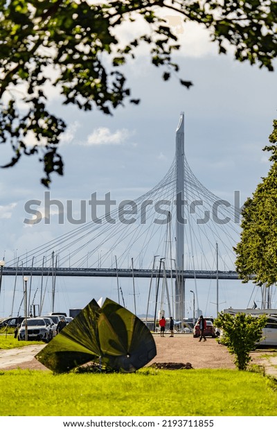 Russia, St.\
Petersburg, 29 July 2022: The embankment of the central yacht club\
at cloudy weather, piers in marina, small sports sailing boats,\
Cable-stayed bridge on\
background