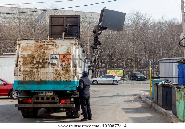 Russia, Vladivostok, 02/22/2018.\
Garbage collector picks up garbage container. Ecology and\
environmental problems of city. Special transport and\
equipment.