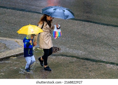 Russia Vyborg 06.06.2022 A woman with her son walk down the street with umbrellas during the rain. High quality photo