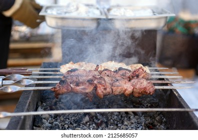 RUSSIA, YAROSLAVL - FEBRUARY 22, 2021. Winter holiday Dad's Day in the forest entertainment Park Zabava. Ready-made food on fire, barbecue - meat skewers and burgers