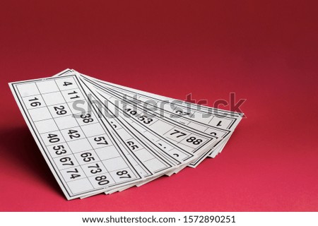 Russian bingo or bingo. White cards with numbers for a board game on a bright red background close-up.