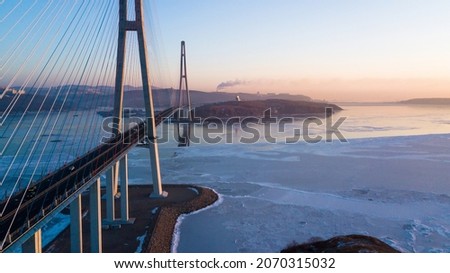 Russian bridge across the Eastern Bosphorus Strait in Vladivostok. View from above. Cars are driving on the roadway of the suspension cable-stayed bridge.