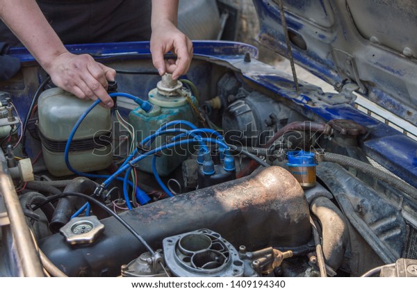 Russian car\
repair. Auto mechanic working in garage. Repair service. Repairing\
engine. Car engine bay open\
hood.