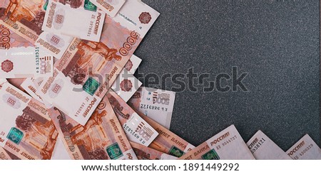 Russian cash banknotes of five thousand rubles, scattered on a gray background