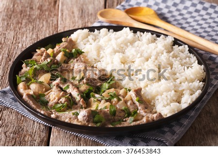 Russian cuisine: beef stroganoff with rice close-up on a plate on the table. horizontal
