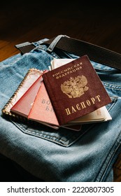 Russian Documents And Cash Money Are Lying On A Stick Of Things, The Man Is Going To Leave Russia So As Not To Participate In The War. Translate: Russian Federation Passport, Military Ticket.