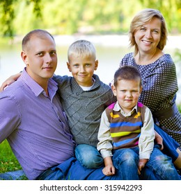 Russian Family, Young Parents And Two Sons In Autumn Park