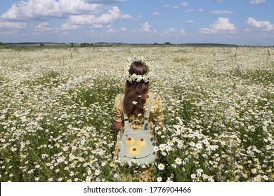 Russian fashionable girl, stylish vintage backpack. Field of wild camomiles. Wild flower field. Retro style in fashion. Summer day in Russia. July nature, countryside. Russian village. Flower wreath
