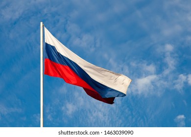 Russian flag  close-up on a pole against a blue sky. The Russian flag develops in a wave in the wind. - Shutterstock ID 1463039090