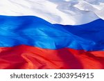 The Russian flag flutters in the wind. Large flag of the Russian Federation outdoors in sunny weather. Bright tricolor background with room for text. Close up. Copy space.