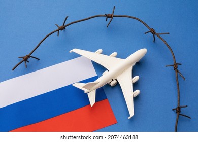 Russian flag, toy plane and barbed wire on blue background, concept of banning aircraft departing from Russia