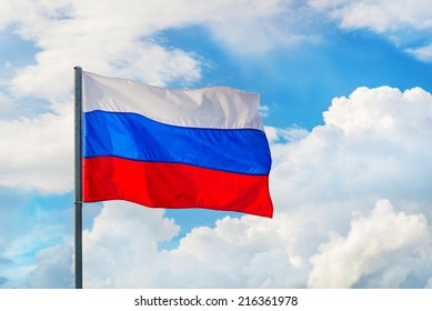 Russian Flag Waving In The Wind Over Blue Sky With White Clouds