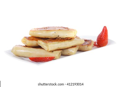 russian food - heap of sweet pancake filled with cottage cheese with strawberry served on white plate isolated over white