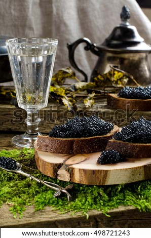 Russian food. Sandwiches with black caviar. Black bread. Vodka. vintage shot glass. silverware. The old Board and moss. Autumn withered leaves.