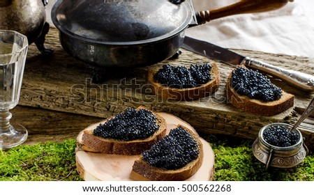 Russian food. Sandwiches with black caviar. Black bread. Vodka. vintage shot glass. silverware. The old Board and moss. Autumn withered leaves.
