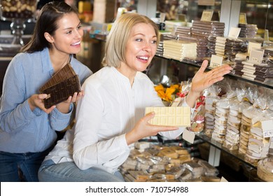 russian friends selecting bars of fine chocolates at confectionery display