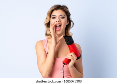 Russian Girl Holding A Hairdryer Isolated On Blue Background Shouting With Mouth Wide Open