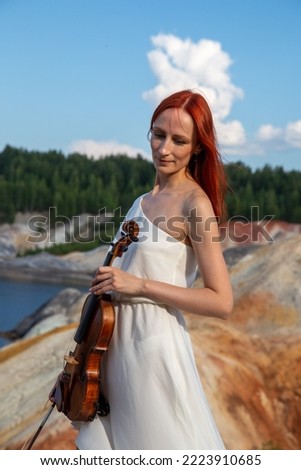 Russian girl with violin in nature quarry with Martian landscapes