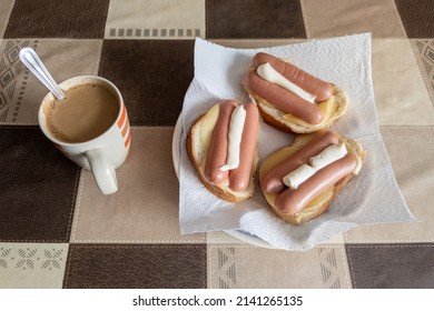 russian hot sandwiches with cheese, sausages and mayonnaise with cup of coffee with milk on table with square pattern.