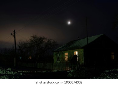 Russian Hut In A Remote Village At Night Against The Background Of Fog And The Moon