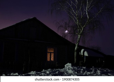 Russian Hut In A Remote Village At Night Against The Background Of Fog And The Moon