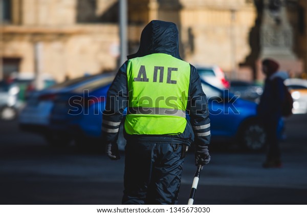 Russian Inspector of\
traffic police highway patrol regulates the movement of transport\
in the center of Moscow, in yellow vest jacket with a sign \