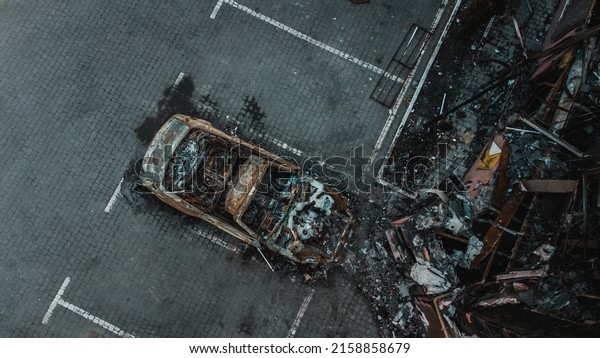 Russian invasion of Ukraine war torn city destroyed\
car burn out. Russia war damage building destruction city war ruins\
city damage car. Disaster area. cars beaten by shrapnel and burnt.\
Drone photo