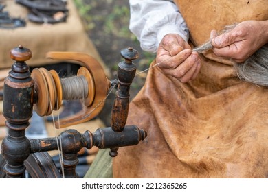 Russian Man Sitting And Spinning A Thread Of Sheep Wool On An Old Spinning Wheel